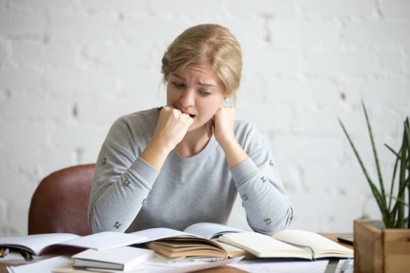 Stressed Girl Sitting With Books and Papers all Over the Desk